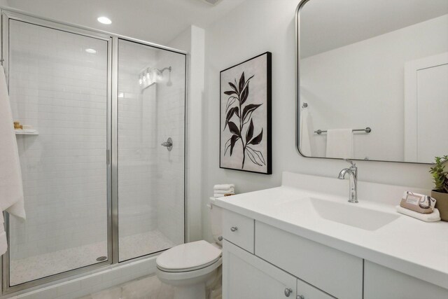 bathroom featuring a shower with shower door, toilet, vanity, and tile patterned floors