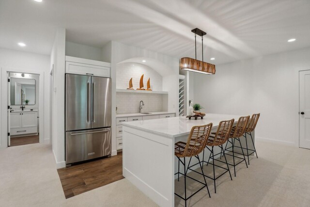 kitchen featuring pendant lighting, hardwood / wood-style floors, white cabinetry, and stainless steel refrigerator