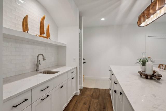 interior space with dark hardwood / wood-style flooring, tasteful backsplash, white cabinets, light stone countertops, and sink