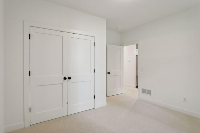 unfurnished bedroom featuring light colored carpet and a closet