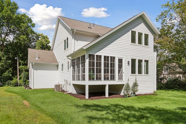 back of property with central air condition unit, a yard, and a sunroom