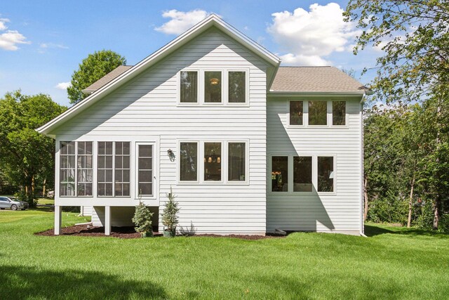 back of house featuring a sunroom and a lawn