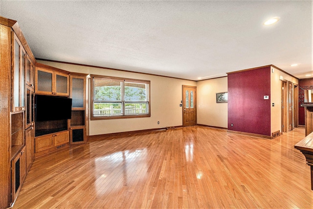 unfurnished living room with crown molding, a textured ceiling, and light wood-type flooring