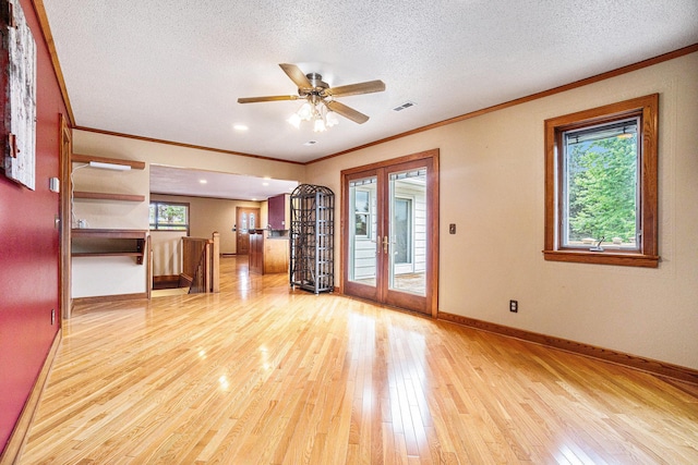 unfurnished living room with french doors, light wood-type flooring, ceiling fan, and a healthy amount of sunlight