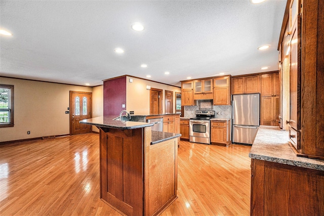 kitchen with stainless steel appliances, a kitchen breakfast bar, light hardwood / wood-style flooring, backsplash, and kitchen peninsula