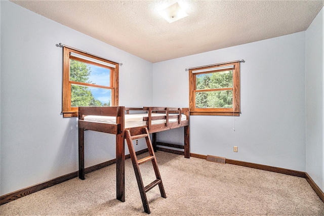 bedroom featuring a textured ceiling and light colored carpet