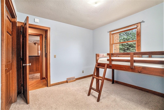 bedroom featuring a textured ceiling and light colored carpet