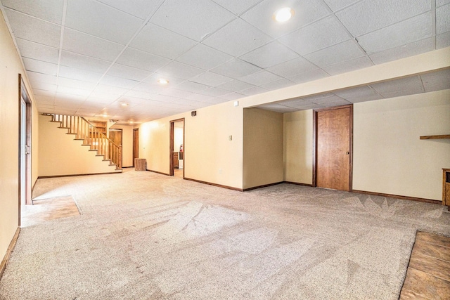 basement featuring a paneled ceiling and light carpet