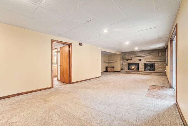 unfurnished living room with a fireplace, light colored carpet, and a drop ceiling