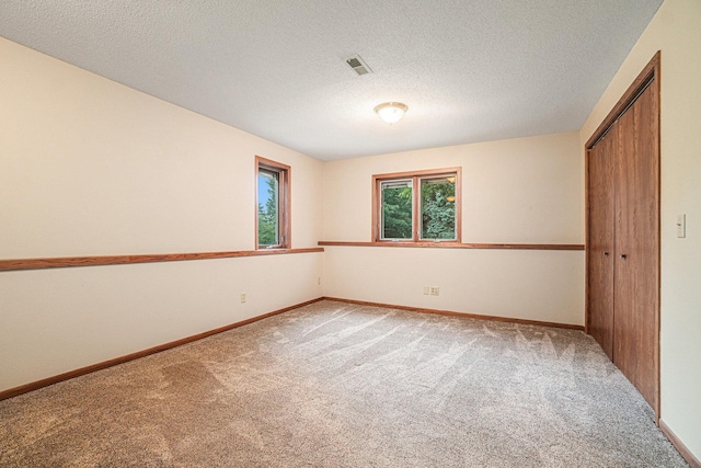 carpeted spare room with a textured ceiling