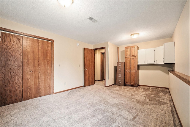 unfurnished bedroom with light carpet, a closet, and a textured ceiling