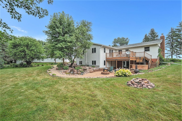 rear view of house with a lawn, a deck, and an outdoor fire pit