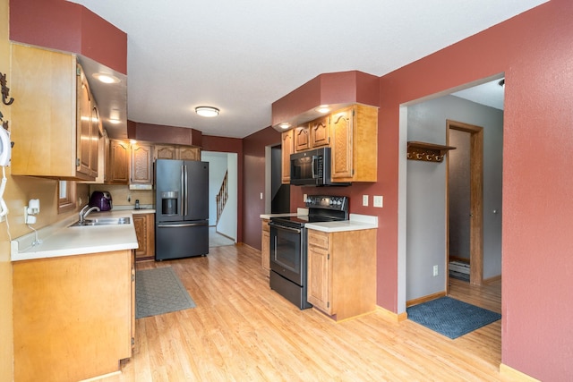 kitchen featuring sink, black appliances, and light hardwood / wood-style floors