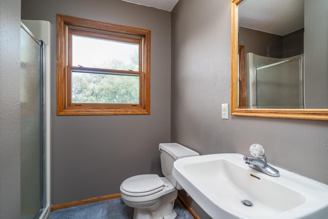 bathroom featuring sink, a shower with door, and toilet