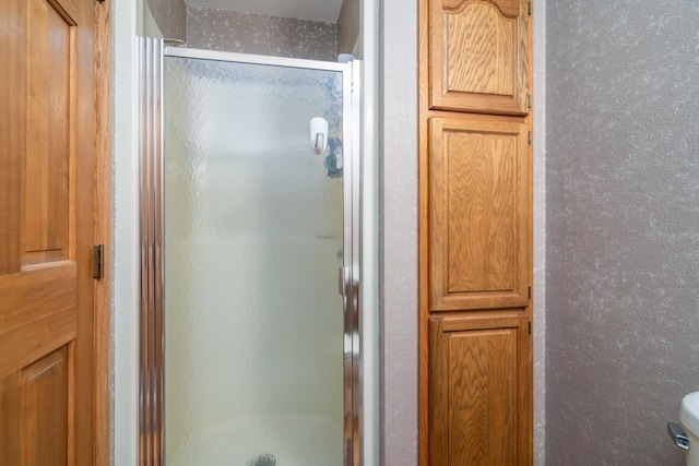 bathroom featuring a shower with shower door, a textured ceiling, and toilet