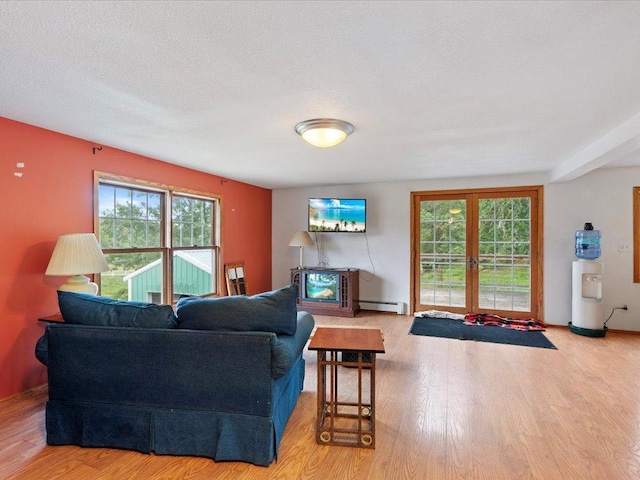 living room featuring a baseboard heating unit, a textured ceiling, wood-type flooring, and a wealth of natural light