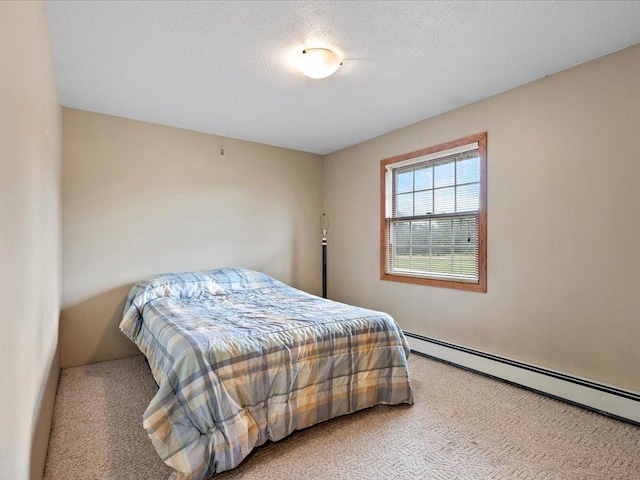 carpeted bedroom with baseboard heating and a textured ceiling