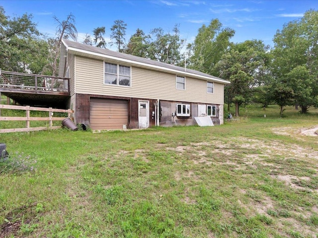 rear view of property featuring a wooden deck, a yard, and a garage