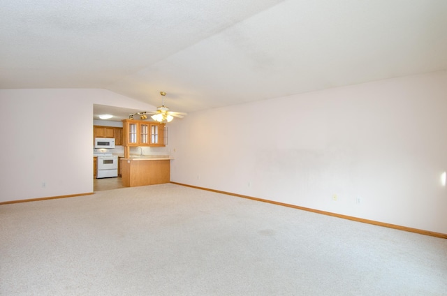 unfurnished living room with lofted ceiling, sink, ceiling fan, and light colored carpet