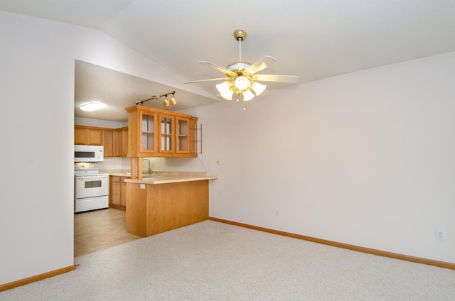 kitchen featuring vaulted ceiling, white appliances, kitchen peninsula, ceiling fan, and sink