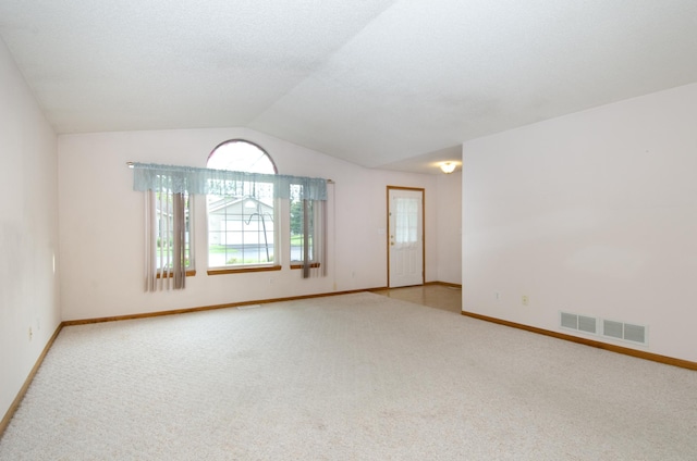 carpeted empty room featuring vaulted ceiling