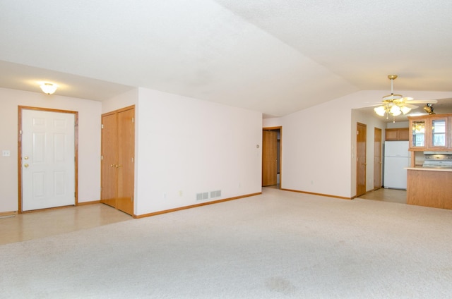 unfurnished living room featuring lofted ceiling, ceiling fan, and light colored carpet