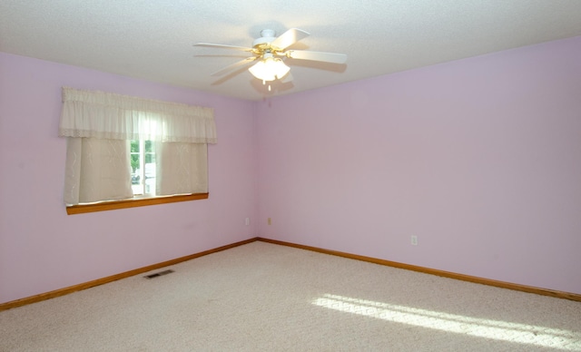 carpeted empty room with ceiling fan and a textured ceiling