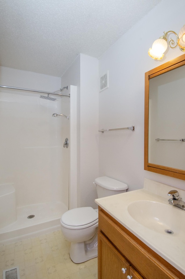 bathroom with vanity, a shower, toilet, and a textured ceiling