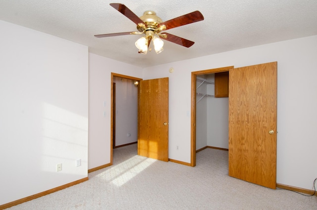 unfurnished bedroom with a textured ceiling, a spacious closet, ceiling fan, and a closet