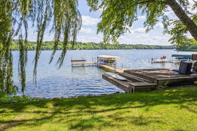 view of dock with a water view and a lawn