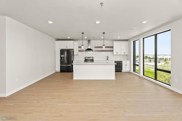 kitchen featuring white cabinetry, stainless steel range with electric stovetop, hanging light fixtures, wall chimney range hood, and fridge with ice dispenser