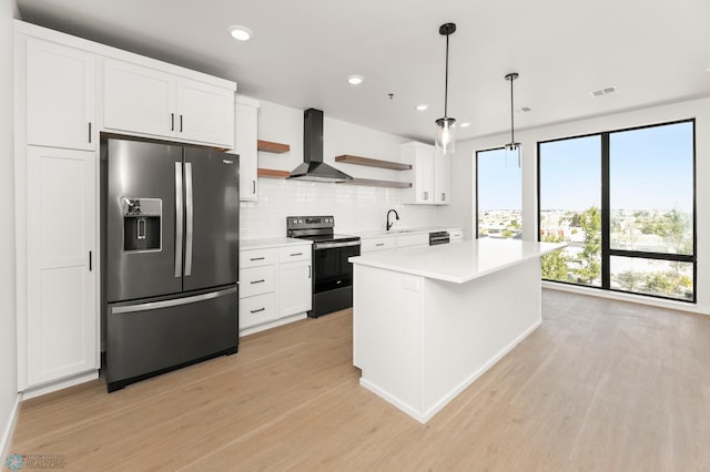 kitchen with stainless steel refrigerator with ice dispenser, wall chimney exhaust hood, pendant lighting, electric stove, and white cabinets