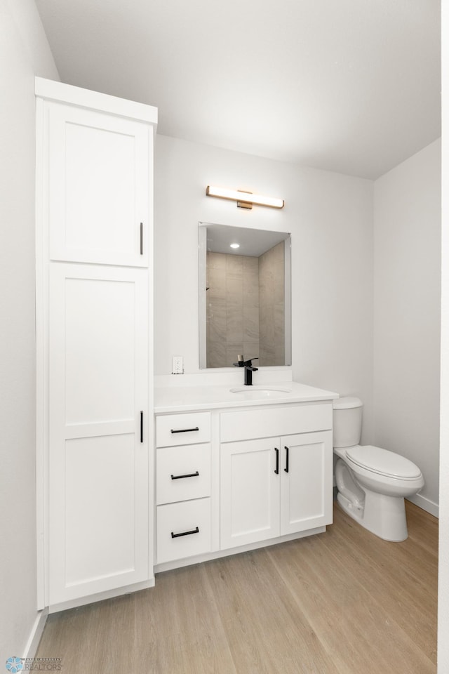 bathroom with vanity, a shower, hardwood / wood-style floors, and toilet