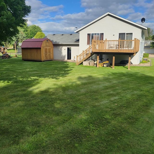 back of property featuring a wooden deck, a yard, and a storage unit