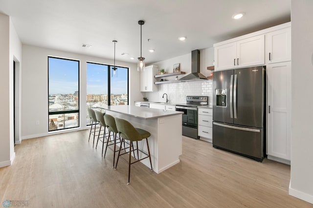 kitchen with a kitchen island, open shelves, stainless steel appliances, white cabinetry, and wall chimney range hood