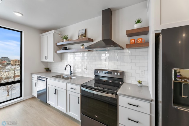 kitchen with a sink, appliances with stainless steel finishes, wall chimney range hood, and open shelves