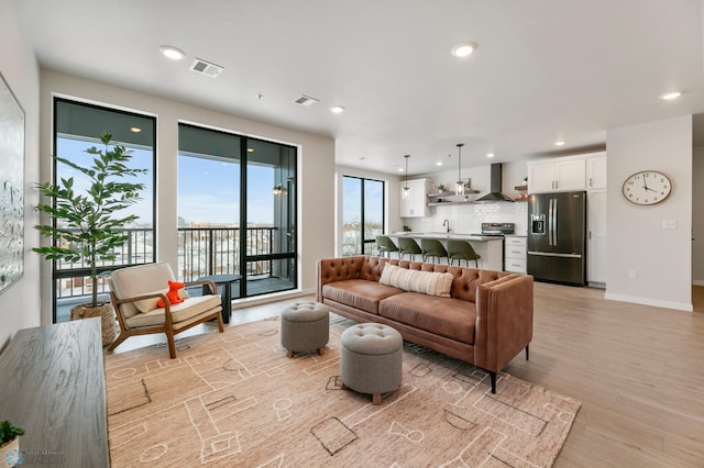 living room featuring recessed lighting, visible vents, baseboards, and light wood-style floors