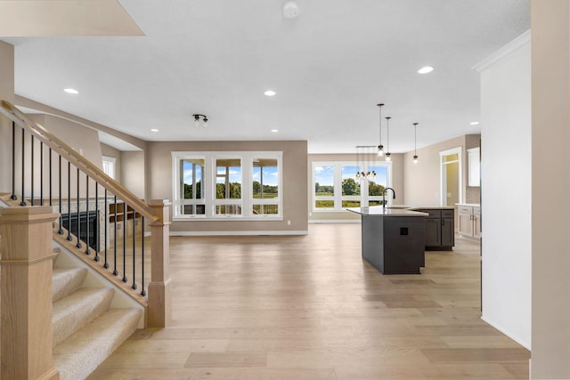 kitchen featuring sink, hanging light fixtures, an island with sink, and light hardwood / wood-style flooring