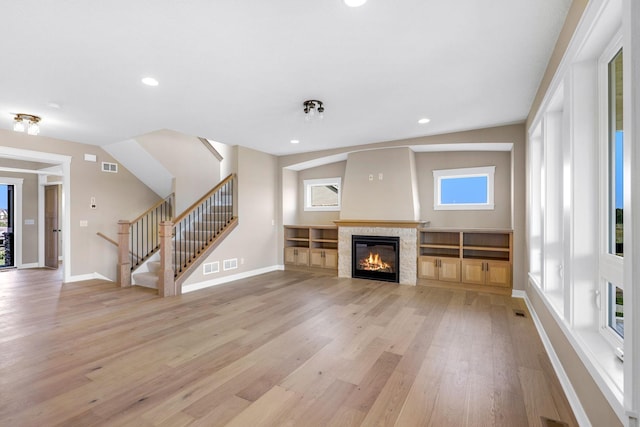 unfurnished living room featuring lofted ceiling, light hardwood / wood-style flooring, and a healthy amount of sunlight