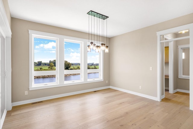 unfurnished room with light hardwood / wood-style flooring and an inviting chandelier