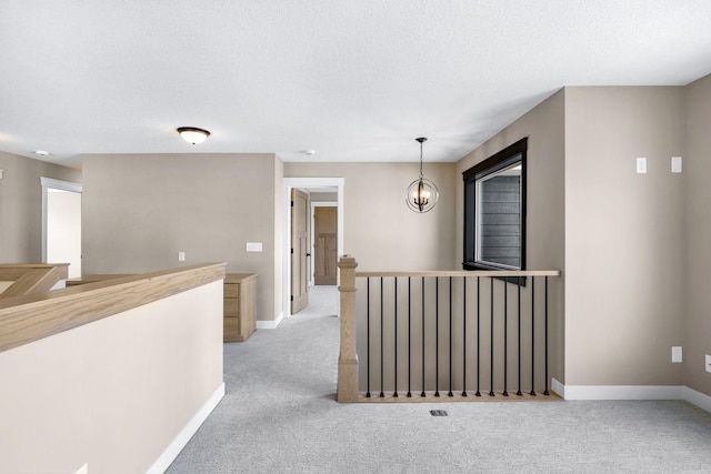 hallway with a textured ceiling and light colored carpet