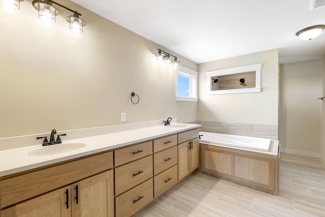 bathroom with vanity, a textured ceiling, tile patterned flooring, and tiled bath