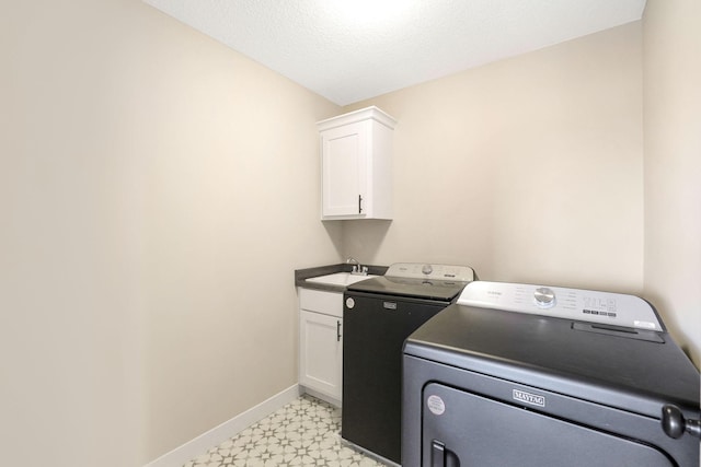 washroom featuring cabinets, a textured ceiling, washing machine and clothes dryer, light tile patterned floors, and sink