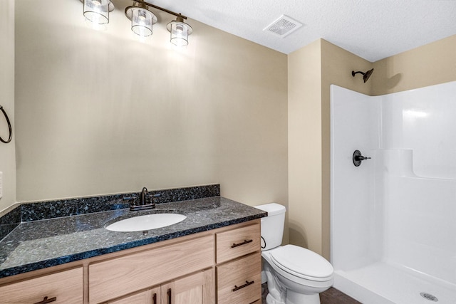 bathroom with a textured ceiling, a shower, toilet, and vanity