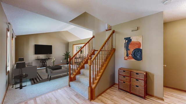 staircase featuring a textured ceiling, lofted ceiling, and hardwood / wood-style floors