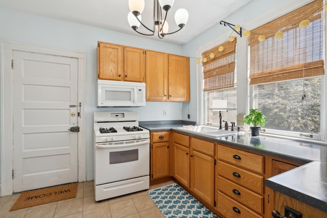 kitchen with white appliances, light tile patterned floors, pendant lighting, sink, and a chandelier