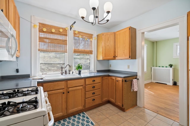 kitchen with white appliances, radiator, light hardwood / wood-style flooring, sink, and a chandelier