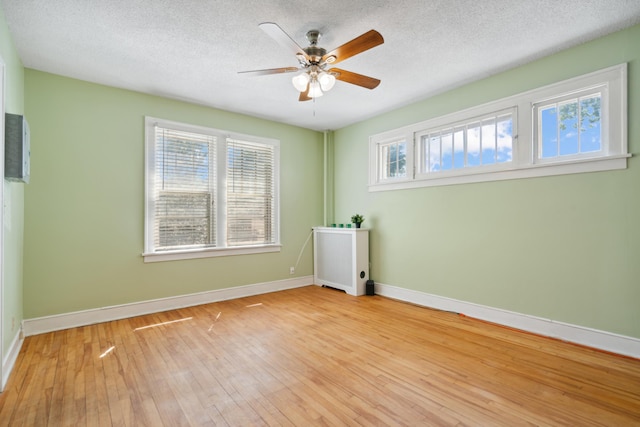 spare room with a textured ceiling, light hardwood / wood-style floors, and ceiling fan