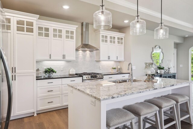 kitchen with stainless steel appliances, decorative backsplash, sink, hardwood / wood-style flooring, and wall chimney exhaust hood