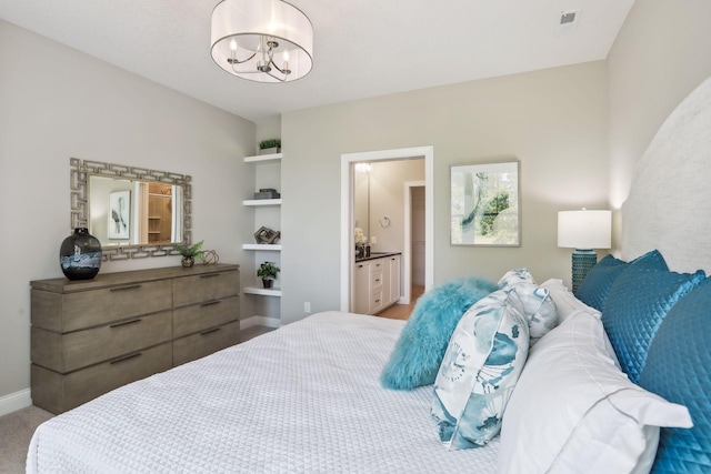 bedroom featuring connected bathroom, a notable chandelier, and carpet floors